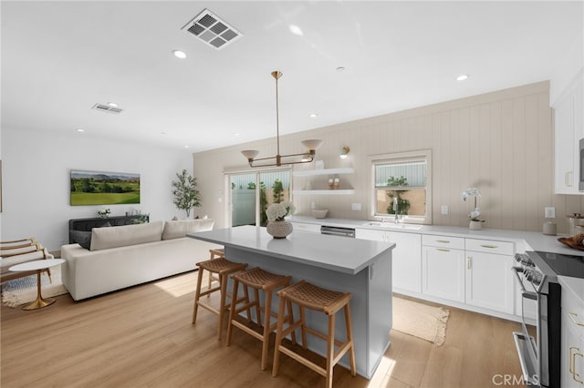 16225 Orizaba Ave, Paramount, CA 90723 - kitchen featuring stainless steel range oven, white cabinetry, a sink, a center island, and a breakfast bar area