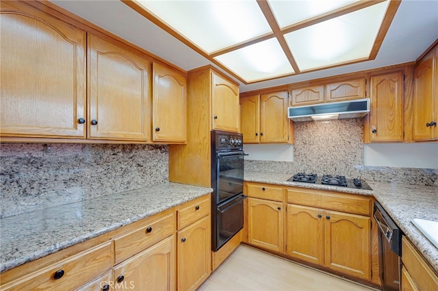 1161 Spazier Ave Unit 4, Glendale, CA 91201 - kitchen with black appliances, under cabinet range hood, tasteful backsplash, light stone counters, and brown cabinets