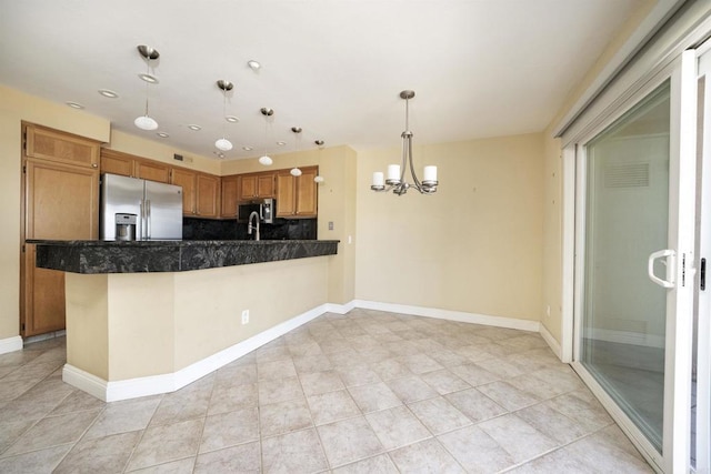 kitchen with stainless steel appliances, a chandelier, dark countertops, decorative light fixtures, and light tile patterned floors