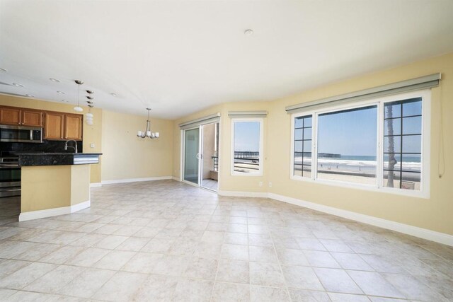 unfurnished living room featuring a chandelier, baseboards, a sink, and light tile patterned floors