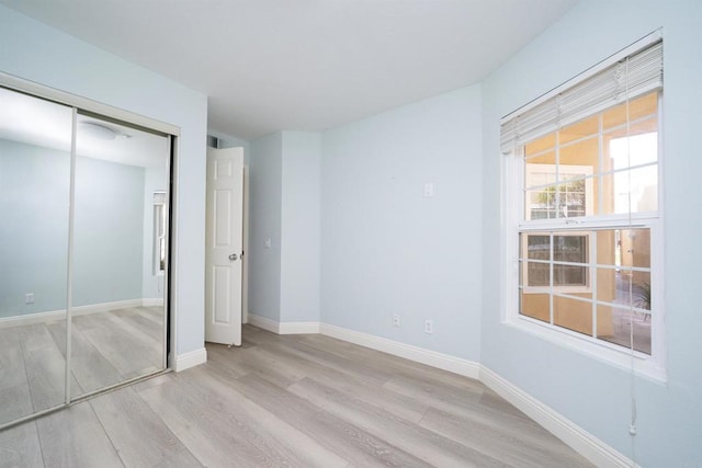 unfurnished bedroom featuring wood finished floors, a closet, and baseboards