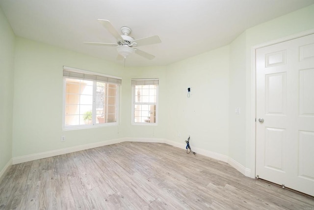 spare room featuring light wood-style flooring, a ceiling fan, and baseboards