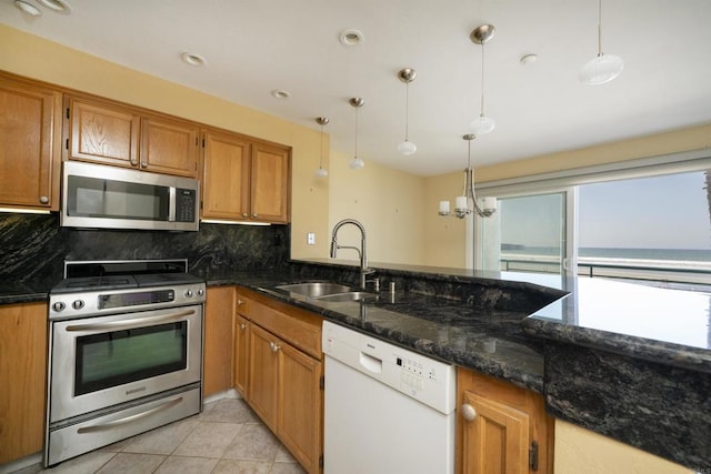 400 N The Strand Unit 27, Oceanside, CA 92054 - kitchen with stainless steel appliances, a sink, decorative backsplash, brown cabinets, and dark stone counters