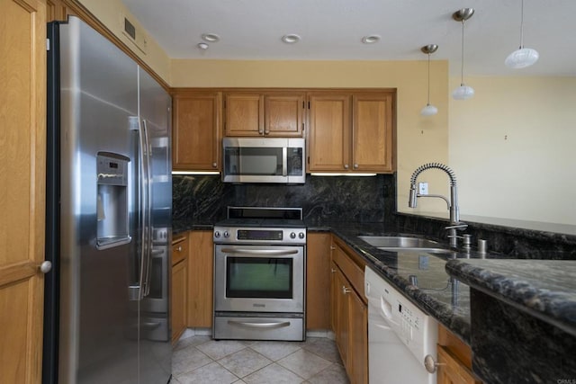 400 N The Strand Unit 27, Oceanside, CA 92054 - kitchen with appliances with stainless steel finishes, brown cabinets, a sink, light tile patterned floors, and backsplash