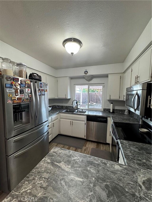 3542 Ponderosa Dr, Oceanside, CA 92058 - kitchen featuring stainless steel appliances, a sink, a textured ceiling, dark wood-style floors, and white cabinetry