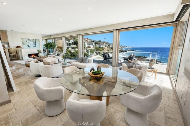 1907 Ocean Way, Laguna Beach, CA 92651 - dining space with stone tile flooring, a water view, a lit fireplace, and recessed lighting