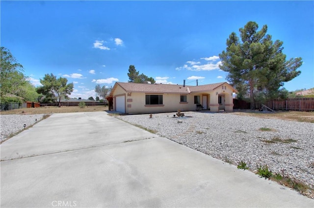 view of front of house with fence, driveway, stucco siding, and a garage