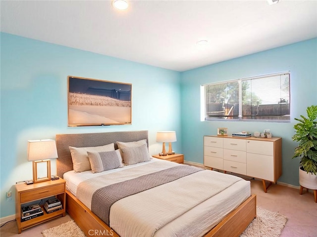 bedroom with light colored carpet and baseboards