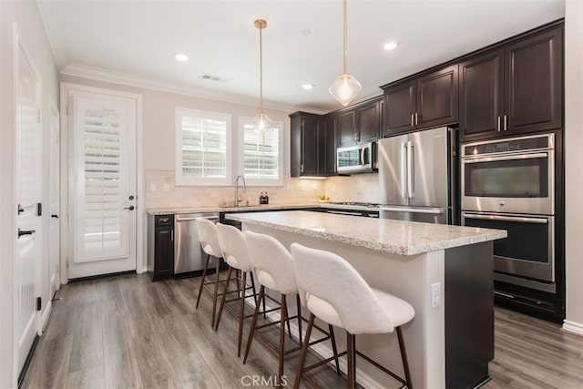 29048 N W Hills Dr, Valencia, CA 91354 - kitchen with stainless steel appliances, a breakfast bar, a center island, dark brown cabinetry, and wood finished floors