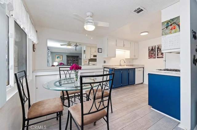 kitchen with blue cabinetry, ceiling fan, white appliances, a sink, and light countertops
