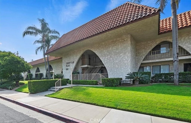 view of front of property featuring a tiled roof, stucco siding, and a front lawn