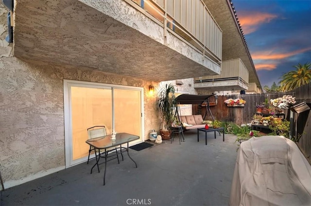 patio terrace at dusk featuring fence