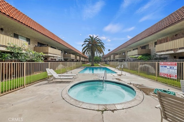 community pool with a community hot tub, fence, and a patio