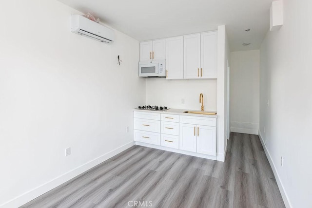 4401 La Clede Ave, Los Angeles, CA 90039 - kitchen with white microwave, a sink, a wall mounted air conditioner, light wood-style floors, and stainless steel gas stovetop