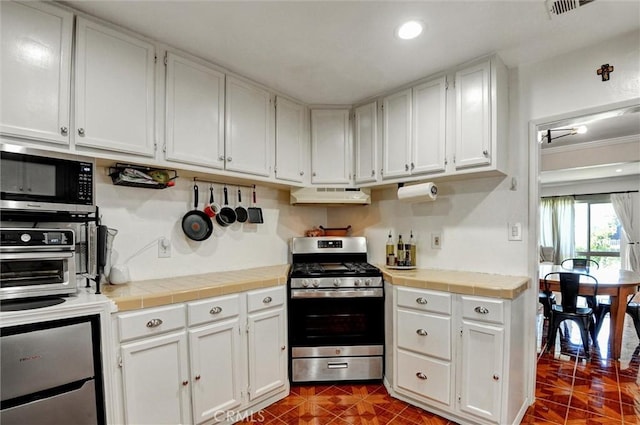 5864 Bonsallo Ave, Los Angeles, CA 90044 - kitchen featuring appliances with stainless steel finishes, under cabinet range hood, white cabinets, tile countertops, and recessed lighting