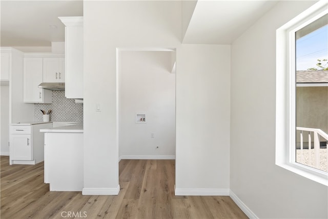 1251 Leighton Ave Unit 1251, Los Angeles, CA 90037 - kitchen with light wood-type flooring, white cabinets, tasteful backsplash, under cabinet range hood, and light countertops