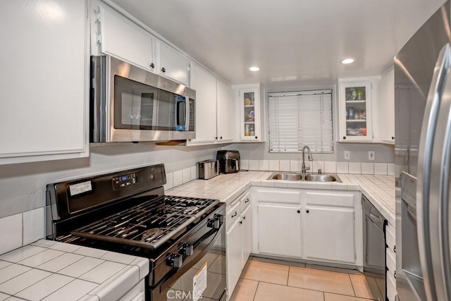 kitchen featuring black appliances, a sink, tile countertops, recessed lighting, and white cabinetry