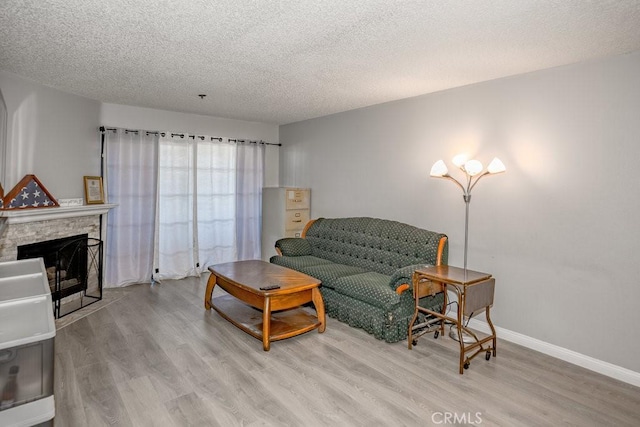 living area featuring wood finished floors, a textured ceiling, a fireplace, and baseboards