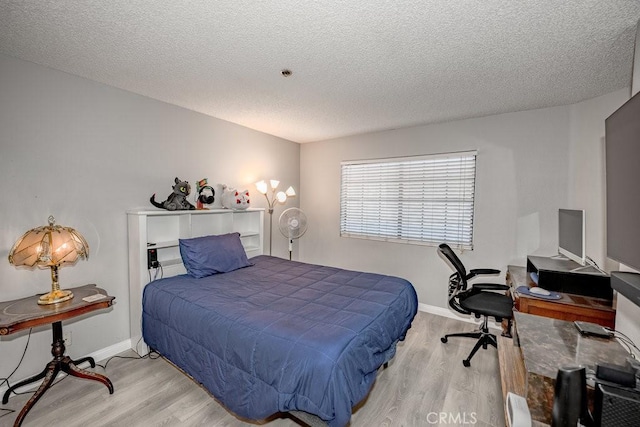 bedroom featuring wood finished floors, a textured ceiling, a desk, and baseboards