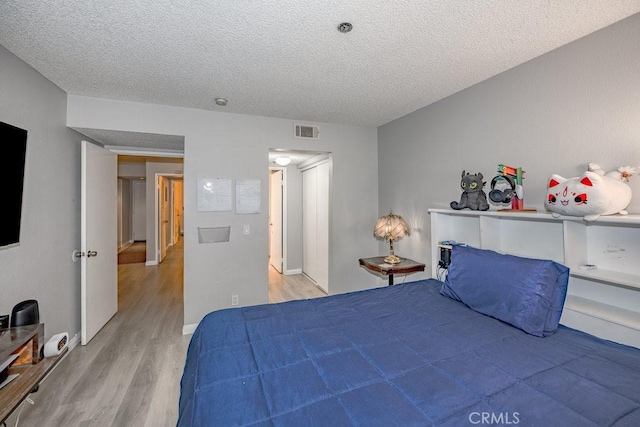 bedroom with light wood-style flooring and a textured ceiling
