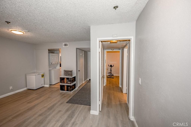hall featuring wood finished floors, a textured ceiling, and baseboards