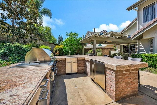 view of patio / terrace featuring a pergola, fence, exterior kitchen, and a bar