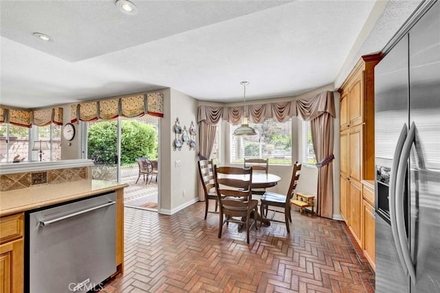 kitchen featuring stainless steel appliances, baseboards, brick floors, light countertops, and recessed lighting