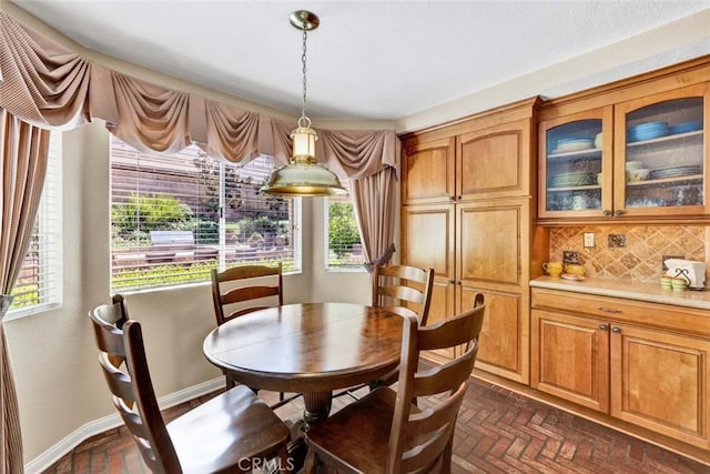 dining space featuring brick floors and baseboards