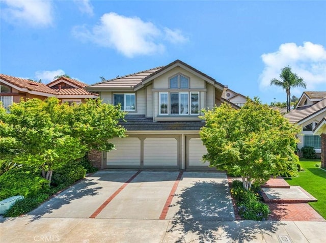 view of front of home with driveway, an attached garage, and a tile roof