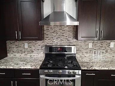 13442 Flower St Unit 15, Garden Grove, CA 92843 - kitchen featuring wall chimney exhaust hood, stainless steel gas range oven, light stone counters, and dark brown cabinetry