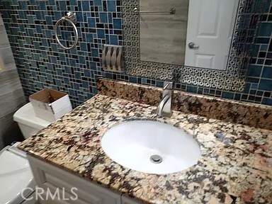 13442 Flower St Unit 15, Garden Grove, CA 92843 - bathroom featuring tile walls, decorative backsplash, vanity, and a tile shower