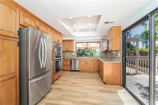 24752 Via, San Anselmo, Mission Viejo, CA 92692 - kitchen with appliances with stainless steel finishes, a raised ceiling, light wood finished floors, healthy amount of natural light, and recessed lighting