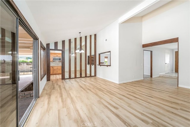 24752 Via, San Anselmo, Mission Viejo, CA 92692 - unfurnished room with light wood-style flooring, baseboards, a chandelier, and high vaulted ceiling