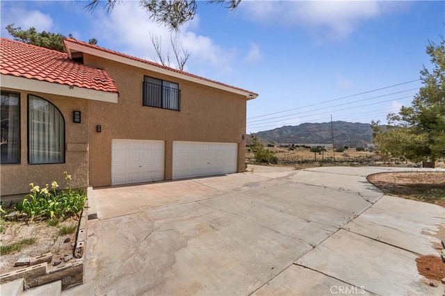 6367 Arrowhead Lake Rd, Hesperia, CA 92345 - view of home's exterior with stucco siding, driveway, a tiled roof, a mountain view, and an attached garage