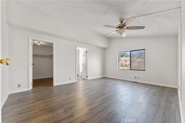 6367 Arrowhead Lake Rd, Hesperia, CA 92345 - unfurnished bedroom featuring dark wood-style floors, a textured ceiling, a walk in closet, a ceiling fan, and a closet