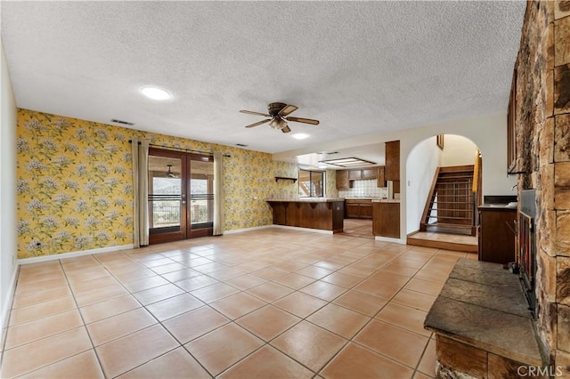 6367 Arrowhead Lake Rd, Hesperia, CA 92345 - unfurnished living room featuring wallpapered walls, ceiling fan, arched walkways, a textured ceiling, and light tile patterned floors
