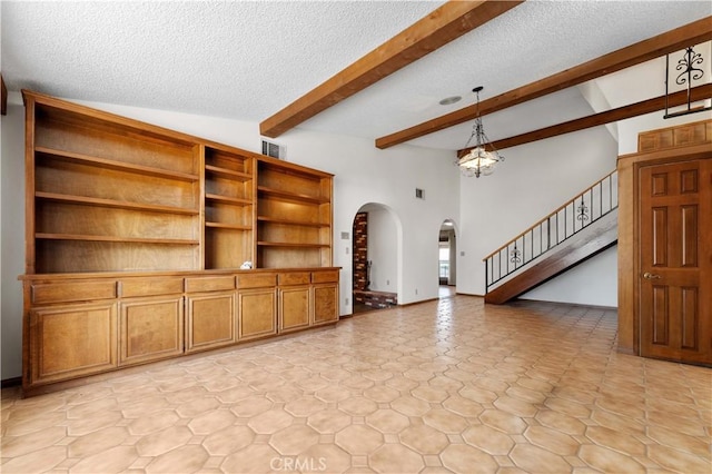 6367 Arrowhead Lake Rd, Hesperia, CA 92345 - unfurnished living room with arched walkways, beamed ceiling, a textured ceiling, stairway, and a chandelier