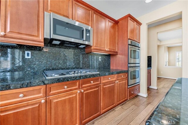 8 Via Del Fico Ct, Lake Elsinore, CA 92532 - kitchen featuring stainless steel appliances, light wood-style flooring, tasteful backsplash, brown cabinets, and baseboards