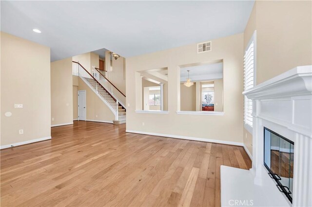 8 Via Del Fico Ct, Lake Elsinore, CA 92532 - unfurnished living room featuring light wood-type flooring, stairs, a fireplace with flush hearth, and baseboards