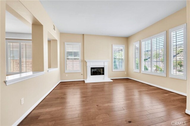 8 Via Del Fico Ct, Lake Elsinore, CA 92532 - unfurnished living room featuring baseboards, hardwood / wood-style floors, and a glass covered fireplace