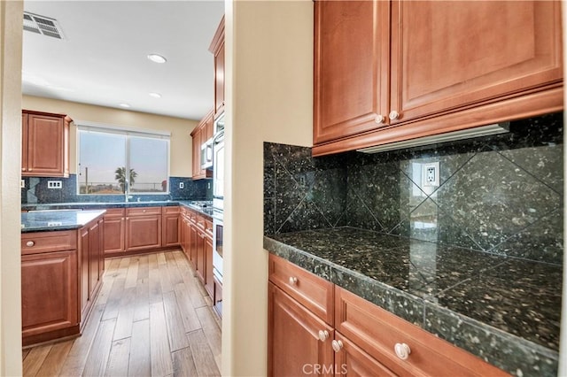 8 Via Del Fico Ct, Lake Elsinore, CA 92532 - kitchen with light wood finished floors, dark countertops, decorative backsplash, recessed lighting, and brown cabinetry