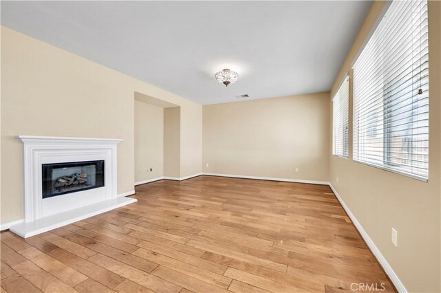 8 Via Del Fico Ct, Lake Elsinore, CA 92532 - unfurnished living room with light wood finished floors, a glass covered fireplace, and baseboards