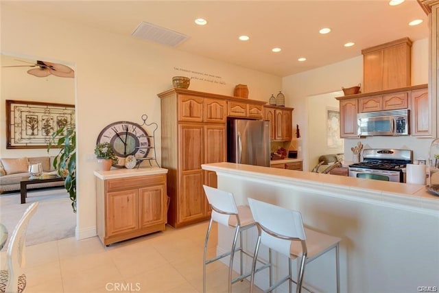 4451 Casa Sierra, Paradise, CA 95969 - kitchen with appliances with stainless steel finishes, recessed lighting, a kitchen bar, light tile patterned floors, and light countertops