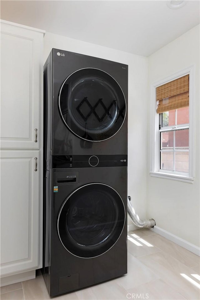 6062 Gaviota Ave, Long Beach, CA 90805 - laundry room featuring stacked washing machine and dryer, cabinet space, baseboards, and light tile patterned floors