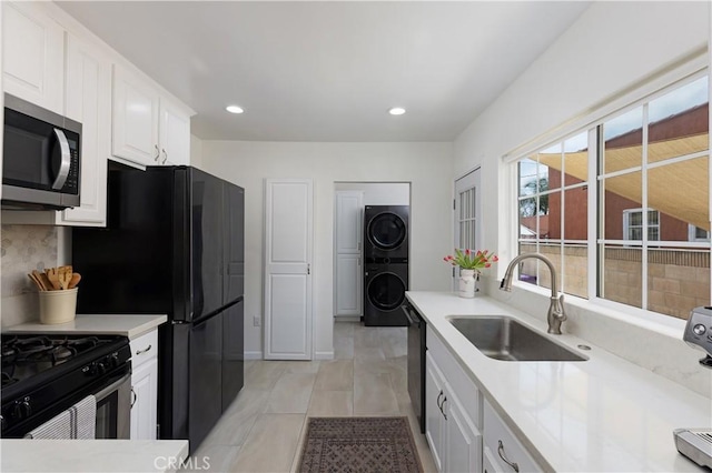 6062 Gaviota Ave, Long Beach, CA 90805 - kitchen with appliances with stainless steel finishes, a sink, stacked washer / dryer, white cabinetry, and light countertops