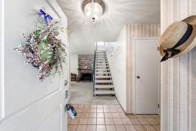 foyer entrance featuring light colored carpet, stairs, light tile patterned floors, a large fireplace, and wallpapered walls
