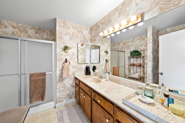 bathroom featuring wallpapered walls, a stall shower, vanity, and baseboards