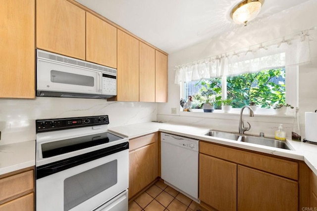 kitchen with white appliances, a sink, light countertops, and light tile patterned floors