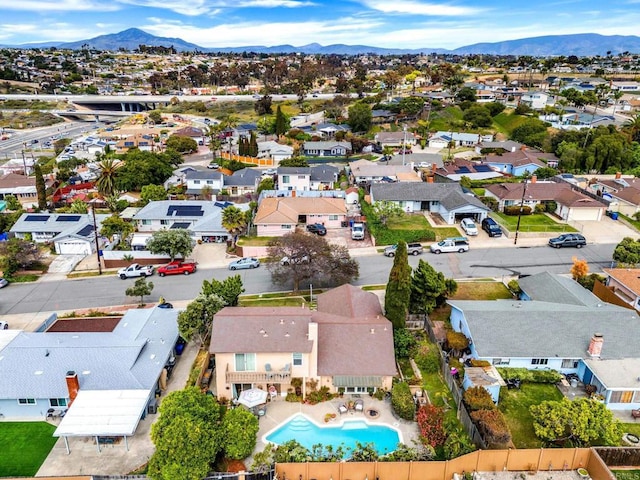 aerial view of residential area featuring a mountainous background and a pool area
