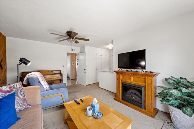 living room featuring light colored carpet, a ceiling fan, and a fireplace